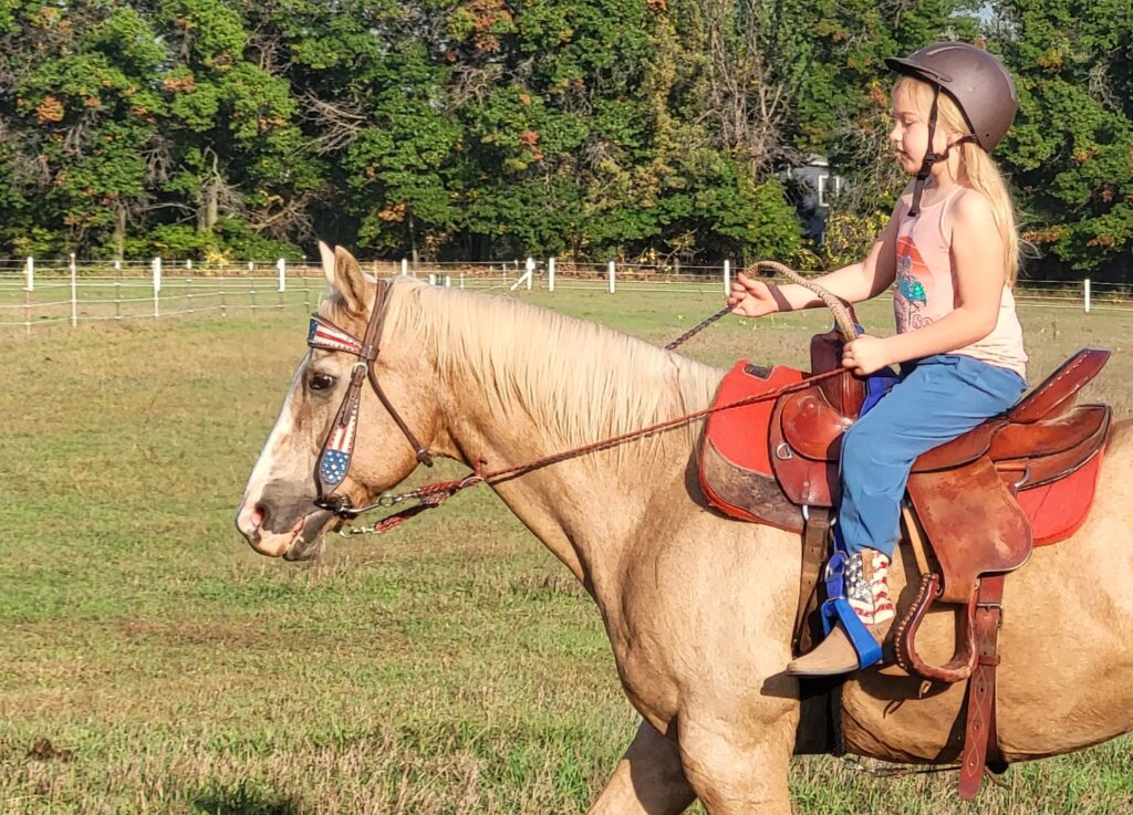 Child riding a palomino horse